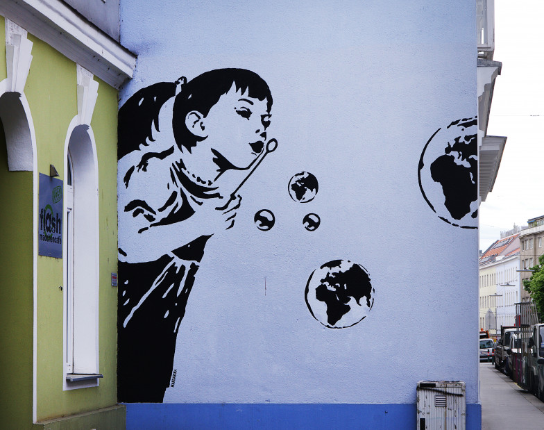 Foto eines Graffito: ein kleines Mädchen bläst Seifenblasen in Form von Weltkuge