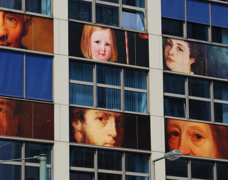 Foto einer Hausfassade, die mit unterschiedlichen Portraits gestaltet wurde.