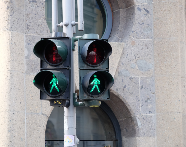Foto: zwei grüne Fußgängerampeln an einer Kreuzung