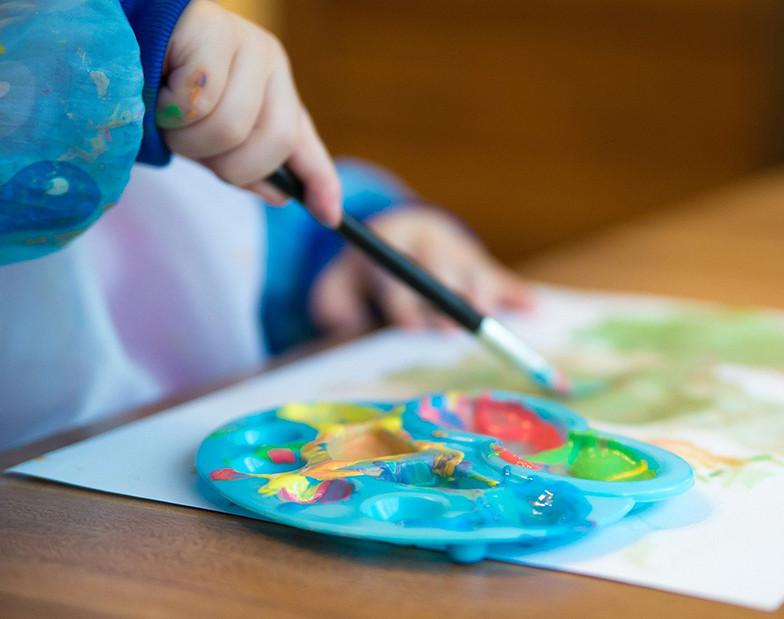 Kinderhand malt Bild mit Tuschefarben