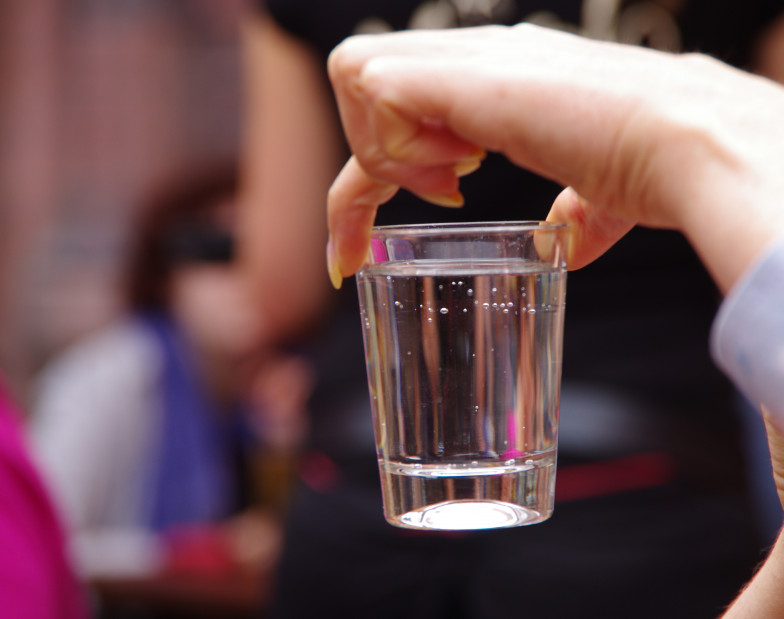Foto: eine Hand hält ein Glas Leitungswasser in die Höhe