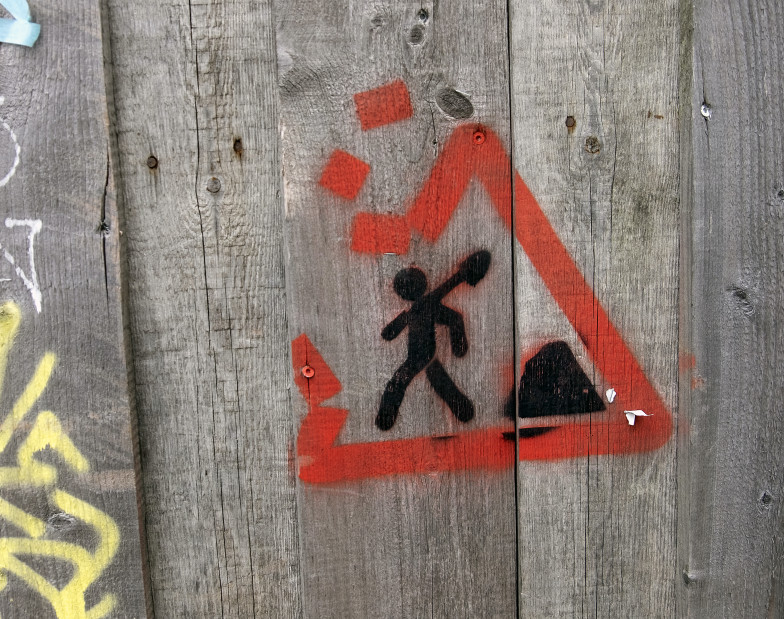 Foto: Graffito eines Baustellenschildes mit durchbrochener roter Umrandungslinie
