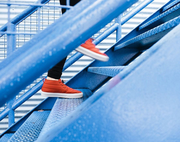 Foto: Füßen in roten Turnschuhen laufen eine Treppe hinauf.