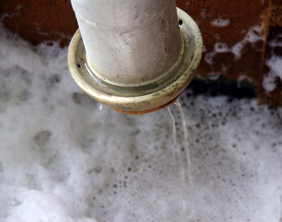 Foto eines Auffangbeckens mit Abwasser, über ein Rohr wird Wasser eingeleitet.