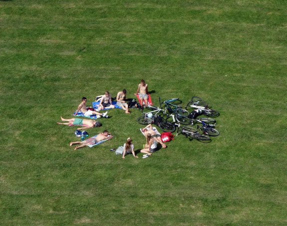 Foto: Jugendliche liegen im Kreis auf einer grünen Wiese