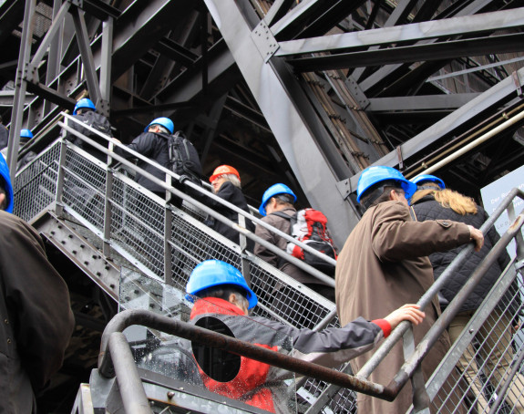 Foto: eine Reihe von Männern mit Bauhelmen auf einer Stahltreppe