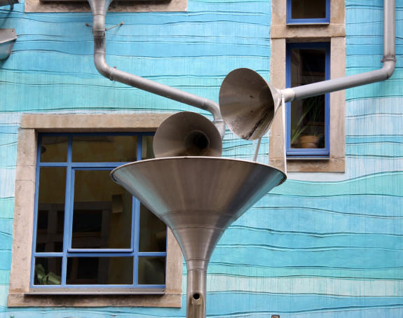 Foto einer mit Rohren und Trichtern künstlerisch gestalteten Hausfassade.