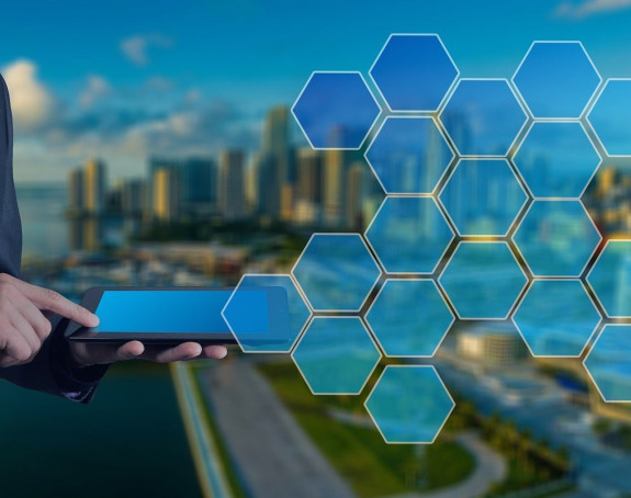 Foto: Mann mit Tablet, im Hintergrund eine Stadt mit grafischen Elementen (bläuliche transparente Hexagone)