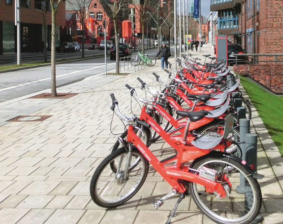 Foto: Reihe roter Leihfarräder auf einem Bürgersteig