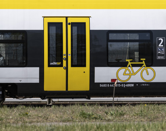 Foto: Detail eines weiß-gelben Nahverkehrszugs - Türen und Fahrrad-Symbol auf der Außenfläche.