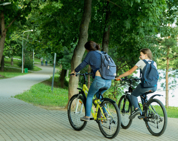 Foto: Zwei junge Frauen fahren Rad durch edinen Park