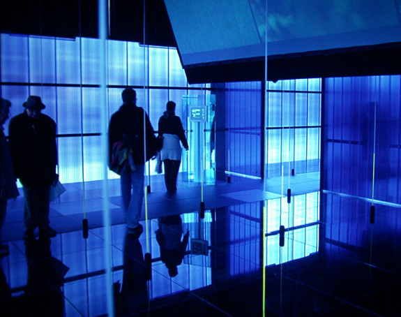 Silhouette von Menschen in dunklem Raum mit blauem Licht und Glaswänden
