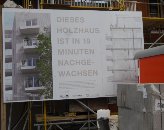 Foto: Holzhaus, Schild im Vordergrund: Dieses Holzhaus ist in 19 Minuten nachgewachsen