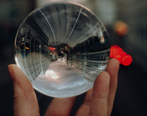 Eine in der Hand gehaltene Glaskugel, in der sich eine Stadt spiegelt