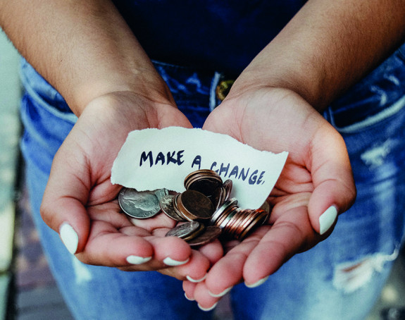 Foto: eine Hand voll Münzgeld, darauf Zettel "Make a change"