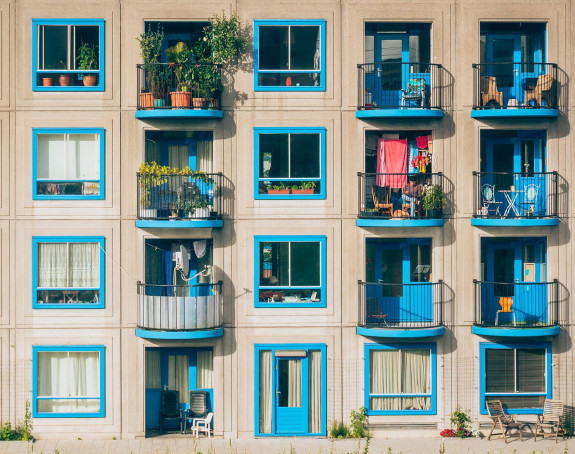 Foto: Fassade eines Wohnhauses mit blauen Fenstern und Balkonen 