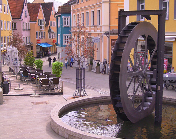 Fußgängerzone Kempten mit Brunnen und Wasserrad im Vordergrund
