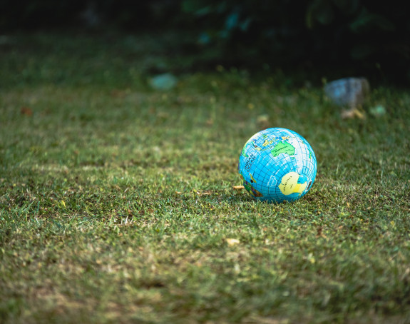 Ein wie ein Globus bedruckter Ball liegt auf einer Wiese