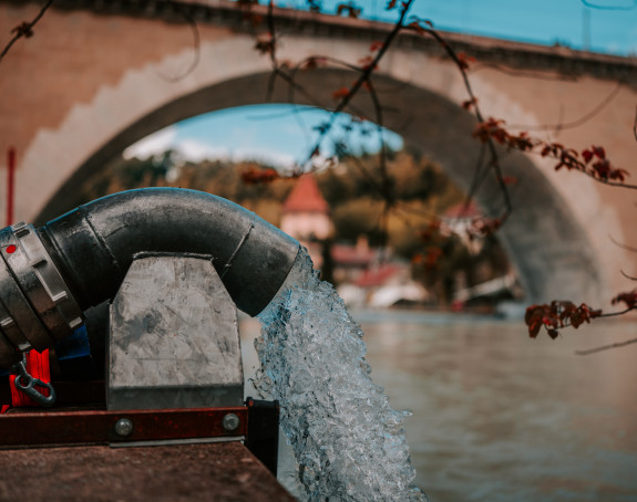 Hydrant aus dem Wasser schießt an einem Fluss vor einer Brücke