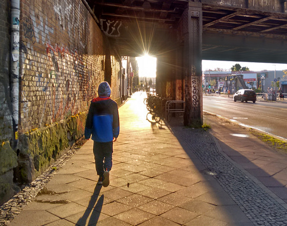 Kind läuft unter S-Bahnbrücke der Sonne entgegen