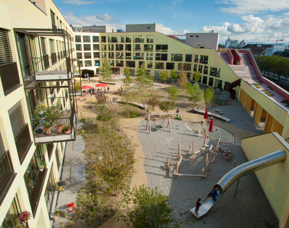 Foto: Blick auf begrünten Innenhof mit Spielplatz einer Genossenschaft 