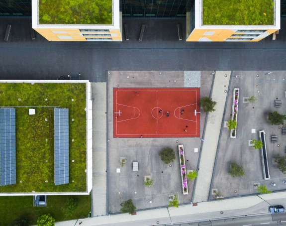 Draufsicht auf Häuser mit begrünten Dächern, Basketballplatz und städtischem Aufenthaltsraum