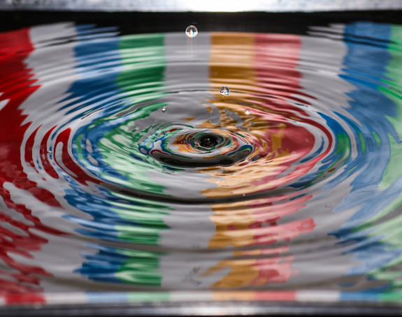 Bild zeigt einen Wassertropfen der auf der Wasseroberfläche kreisförmige Wellen erzeugt.