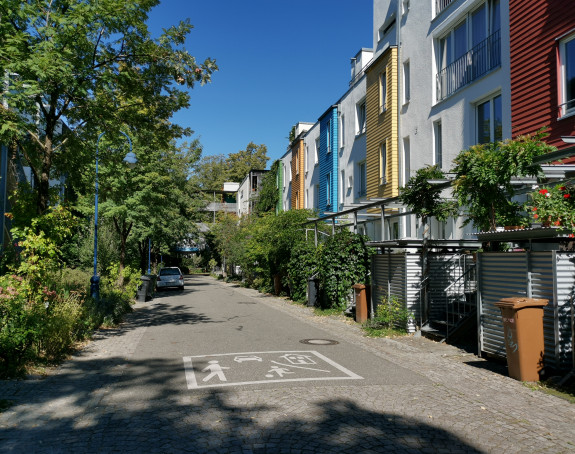 Das Foto zeigt eine Spielstraße, die von begrünten Wohnhäusern gesäumt wird
