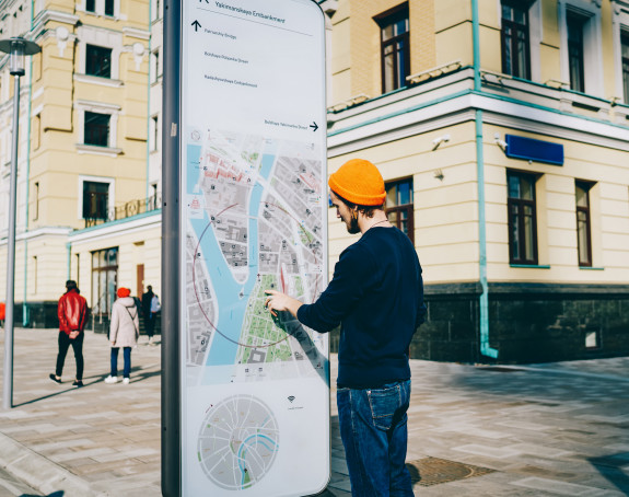 Junger Mann vor Stadtplan in Form eines Smartphones, Straßenszene
