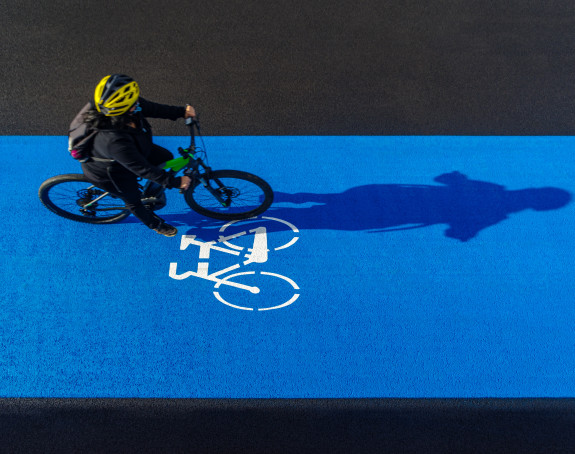 Blauer Radweg mit Fahrradfahrer aus der Luft fotografiert.