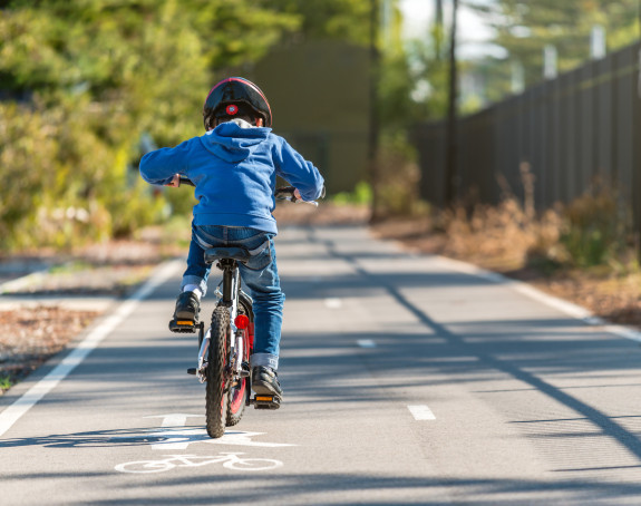 Kind fährt mit Fahrrad auf einem Radweg