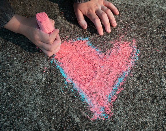 Kind malt mit Kreide ein Herz