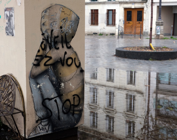 Foto eines Graffito: ein Mädchen sitzt zusammen gekauert an der Straße