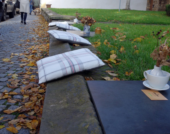 Foto: Sitzkissen und Kaffeetasse auf einer öffentlichen Bank in einer Innenstadt