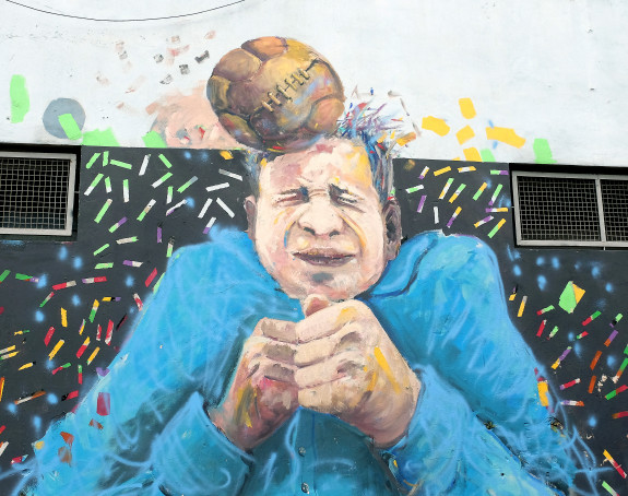 Foto: Graffito eines Menschen, der von einem Fußball am Kopf getroffen wird