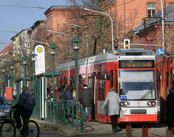 Foto: rote Straßenbahn mit ein- und aussteigenden Fahrgästen