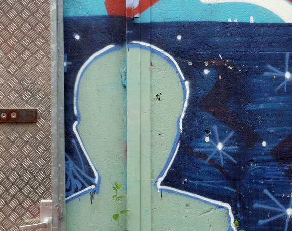 Foto eines Graffito: Umriss eines Menschen vor einer blauen Wand