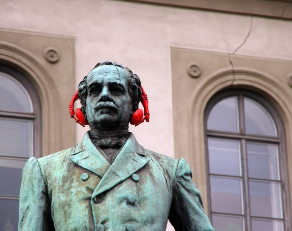 Foto: Bronzestatue mit roten Kopfhörern