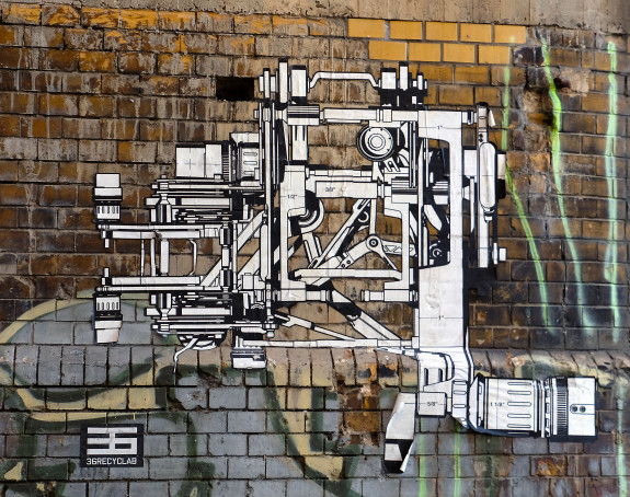 Foto: geklebtes Wandbild einer fiktiven Maschinenzeichnung auf einer Ziegelwand