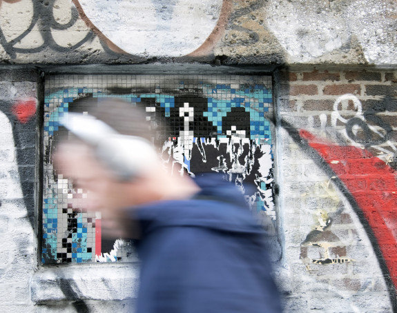 Foto: Mensch im Vorübergehen (unscharf) vor einer farbigen Hauswand