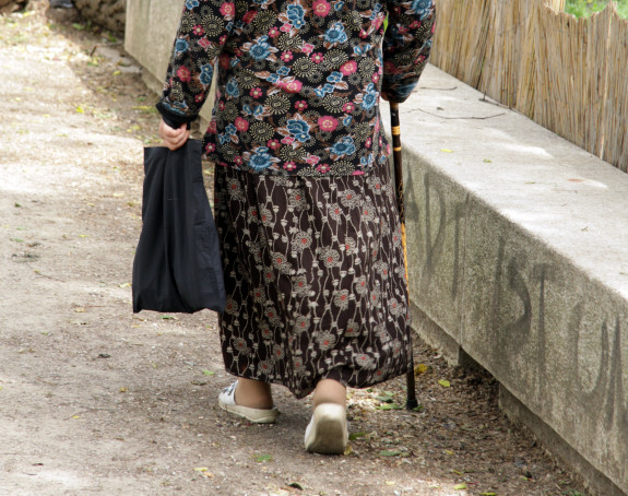 Foto: Eine alte Frau geht an einem Stock, Aufnahme von hinten