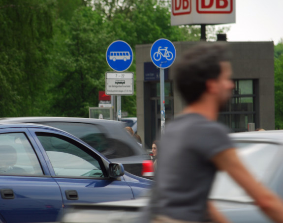 Foto: ein Radfahrer und PKW vor einer DB-Station