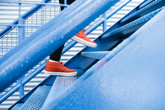 Foto: Füßen in roten Turnschuhen laufen eine Treppe hinauf.
