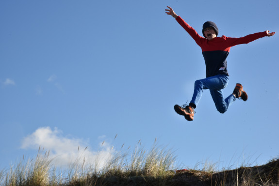 Foto: ein Junge springt in hohem Bogen über eine Düne