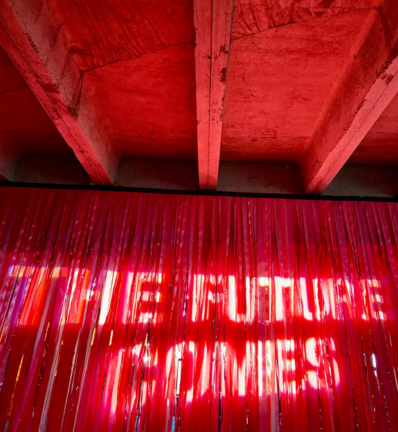 Lichtinstallation auf rotem Vorhang mit den Worten The Future Comes